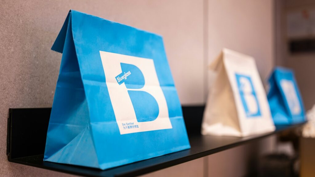 Blauwe papieren verpakking met logo en merknaam op een plank – voorbeeld van consistente branding.