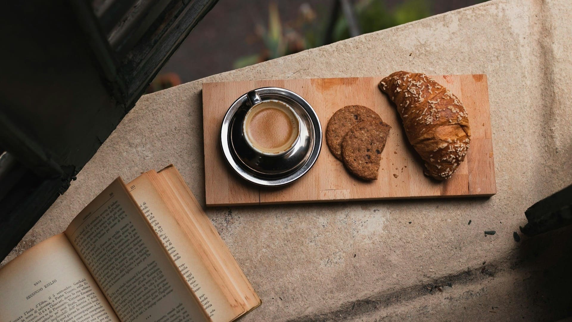 Koffie met croissant en boek op vensterbank als moment van rust binnen duurzame keuzes en bewuste leefstijl