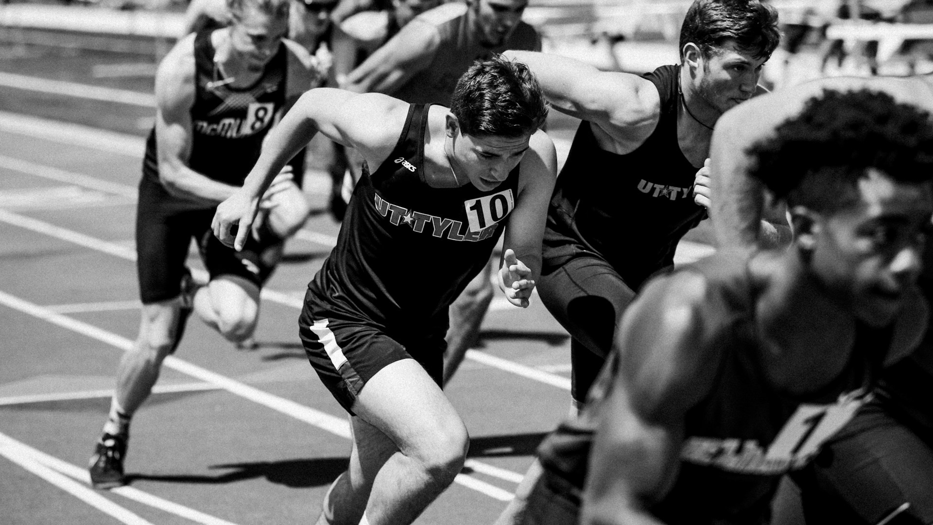 Atleten starten krachtig aan een hardloopwedstrijd op de atletiekbaan – beweging inpassen in competitieve vorm.