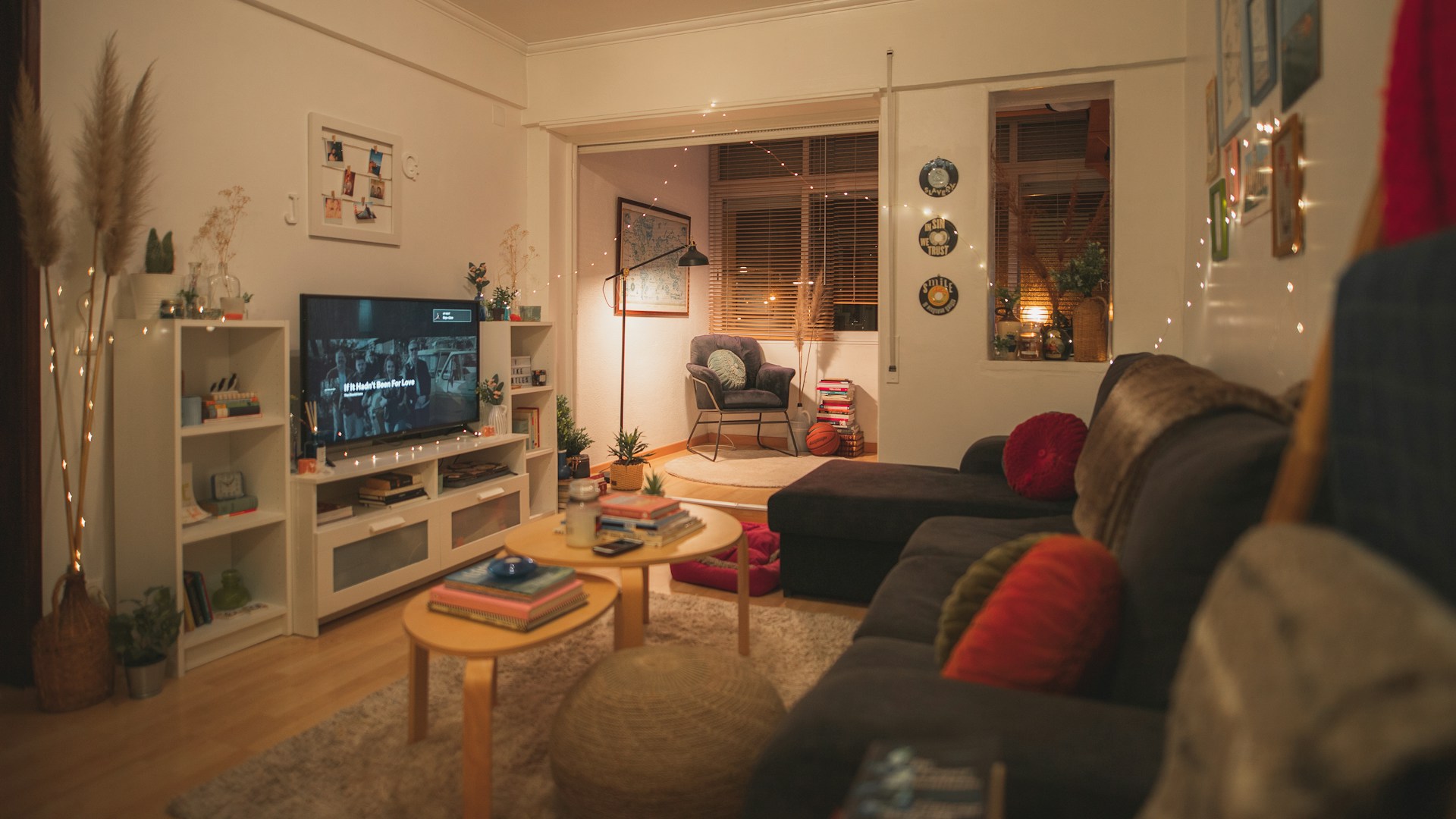 Gezellige woonkamer in de avond met warme sfeerverlichting, zachte bank, vloerkleed en tv-meubel