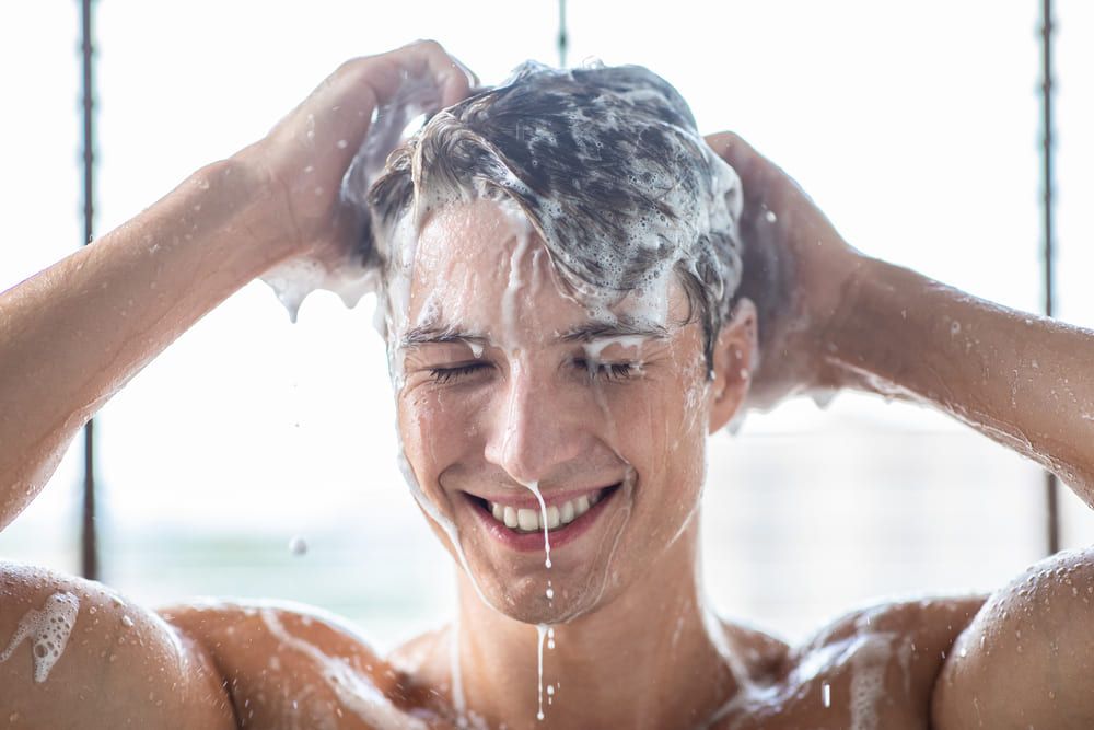 man wast haren met shampoo na het sporten