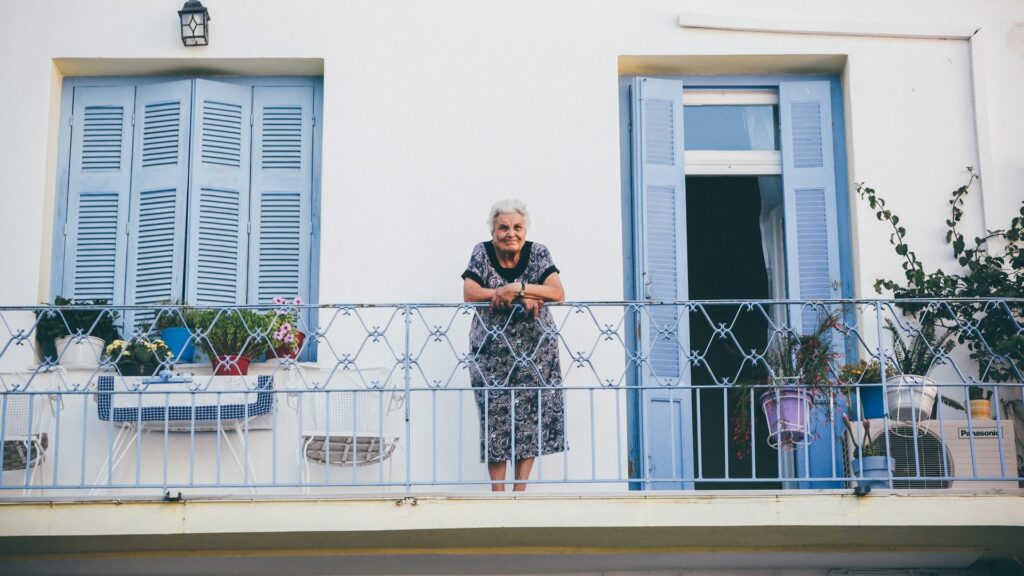 Oudere vrouw op balkon bij haar woning als voorbeeld van zelfstandig wonen op latere leeftijd