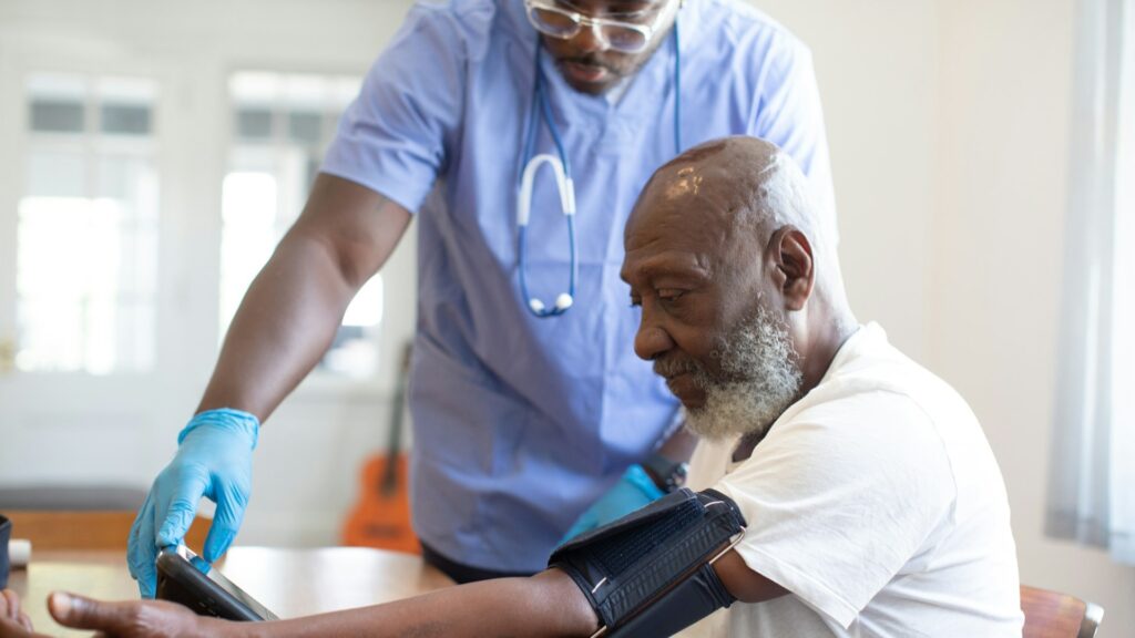 Zorgverlener meet bloeddruk van oudere man in een zorginstelling, vertrouwelijk melden in de zorg centraal.
