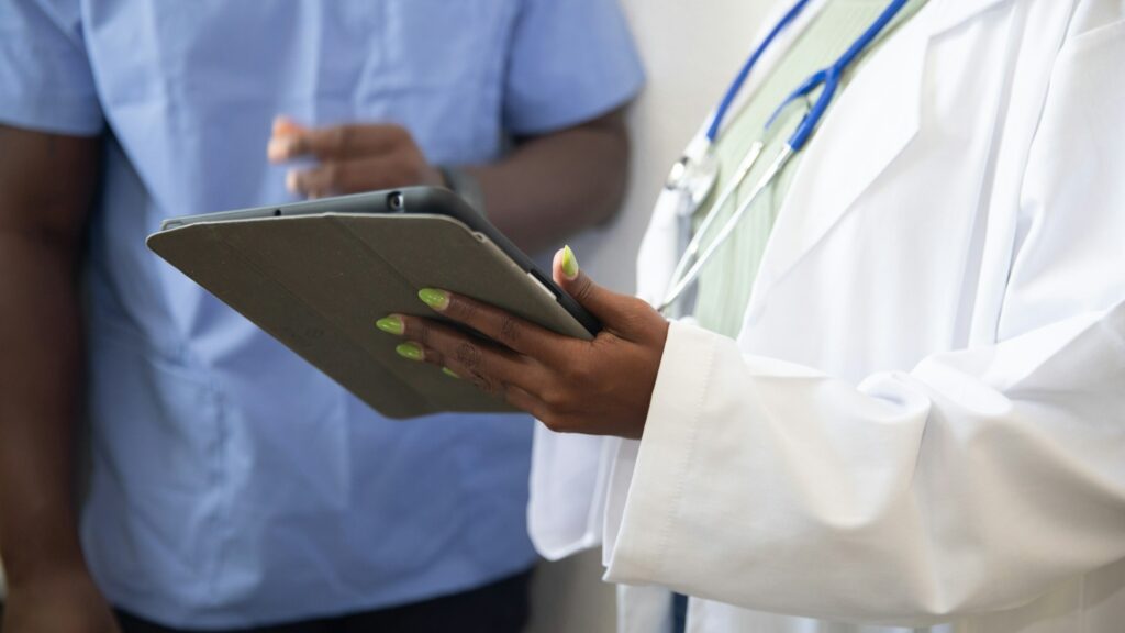 Arts met stethoscoop bespreekt gegevens op tablet, onderdeel van vertrouwelijk melden in de zorg.
