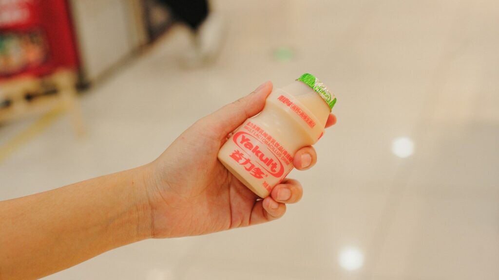 Hand houdt flesje Yakult, een probiotische gefermenteerde drank met levende culturen
