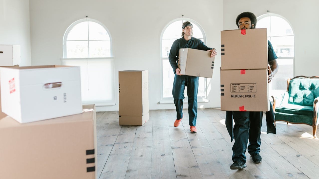 Verhuizers dragen dozen in lege woning tijdens duidelijke planning verhuizing